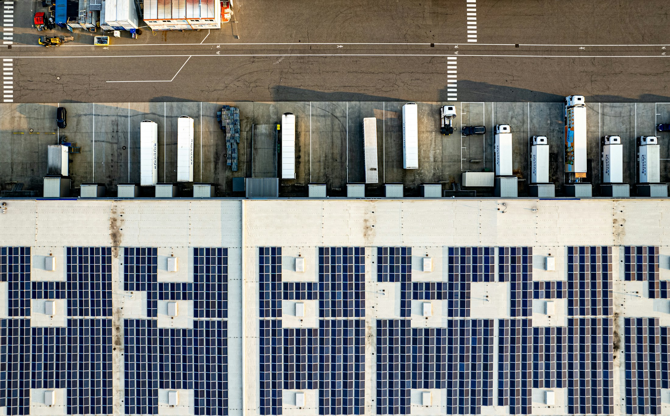 Luftaufnahme einer Industriehalle mit großflächiger Photovoltaikanlage auf dem Dach